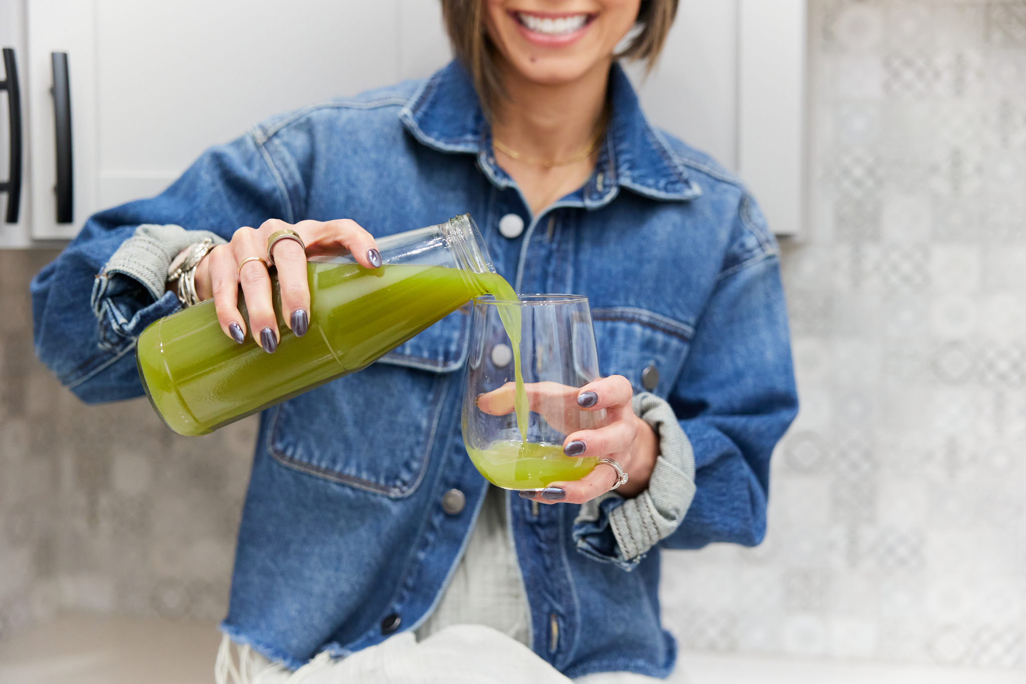 woman pouring green juice into glass